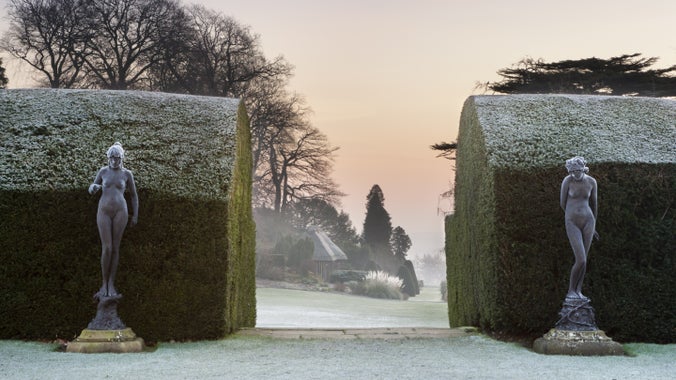 Frost covered statues and yew hedges in the garden at Chirk Castle, Wrexham
